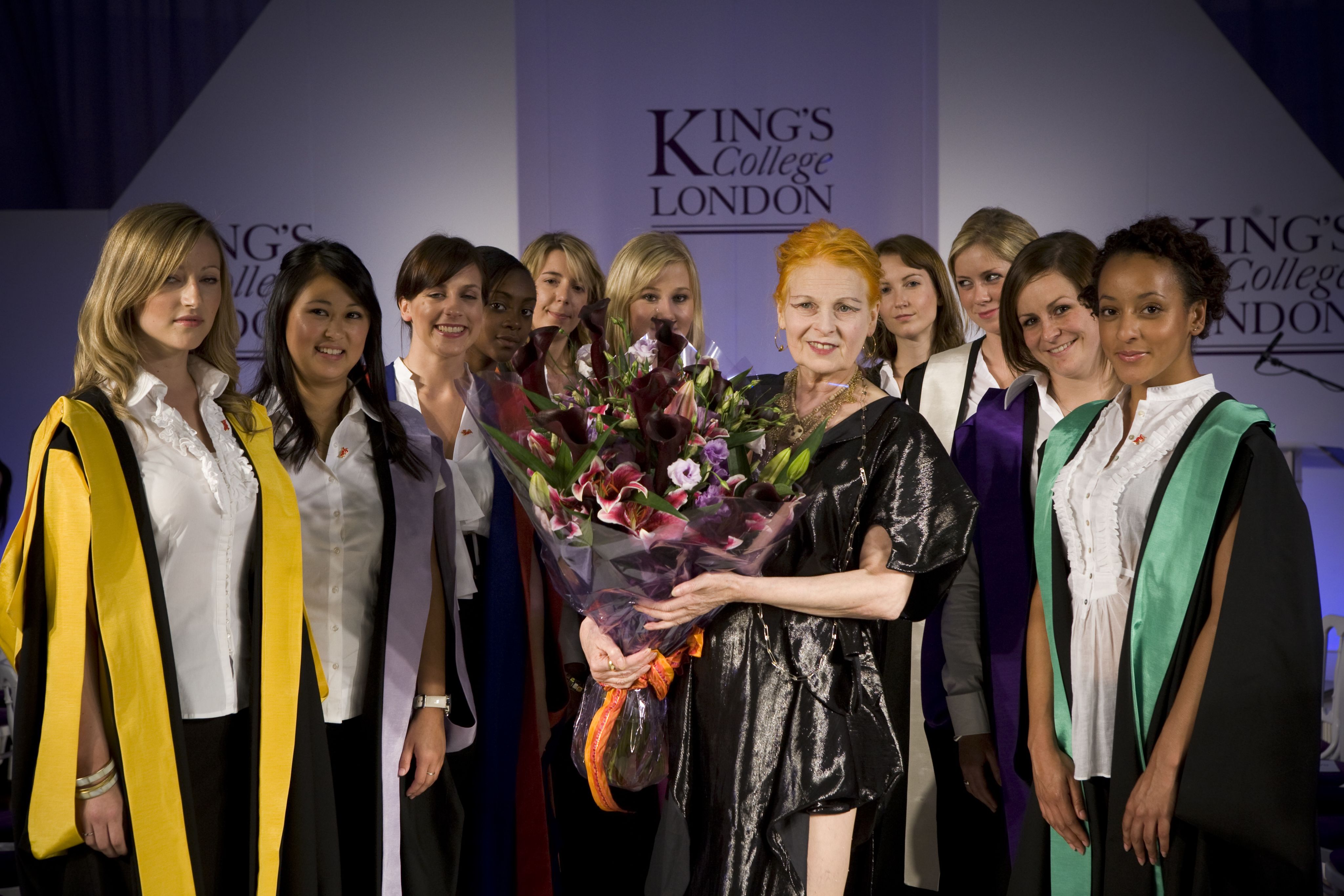 Vivienne Westwood holding a bouquet of flowers, posing with graduates of different faculties for a photo.