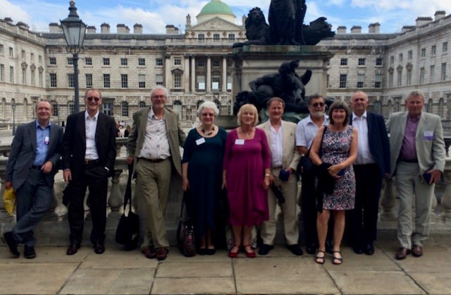 10 members of the Geography class of 1974 smile outside Somerset House.
