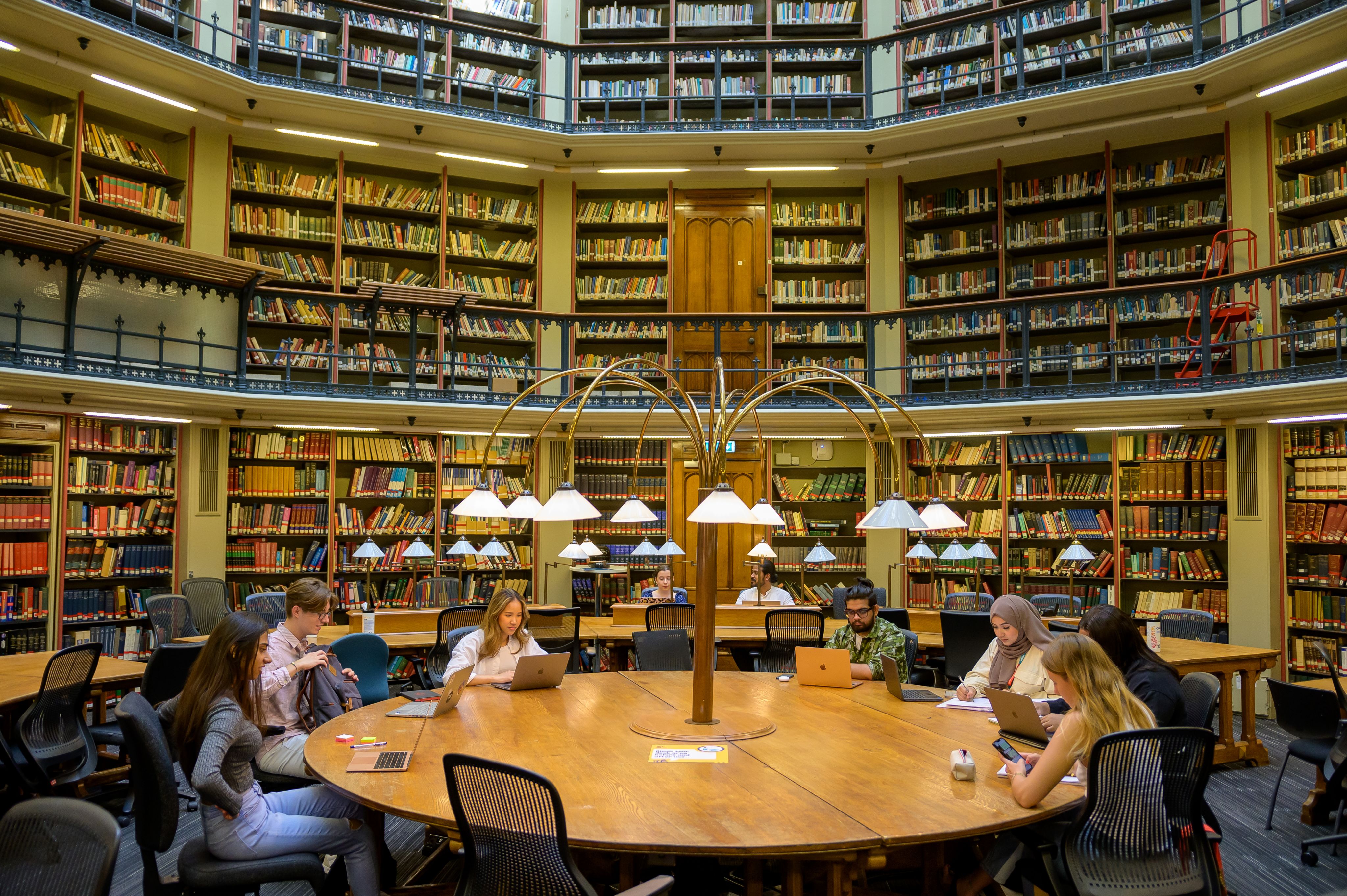 A group of students sit at the circular table in the round reading room of the Maughan Library