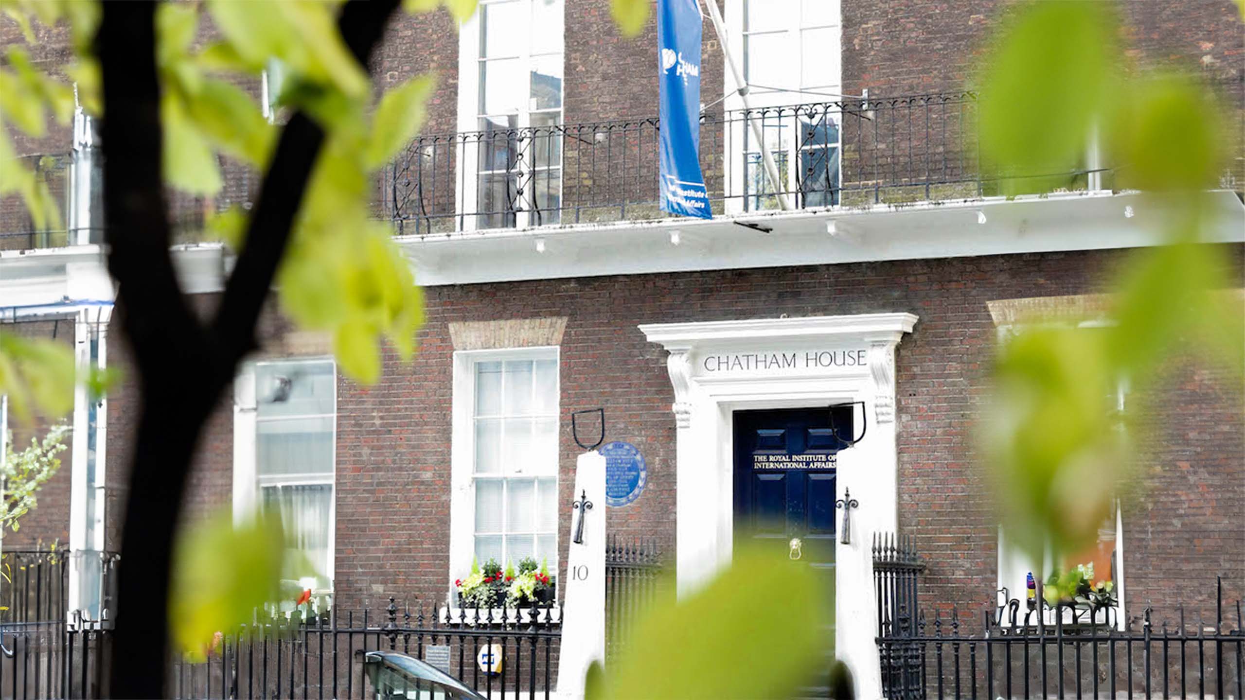 Chatham House pictured from the front. It is framed by leaves.