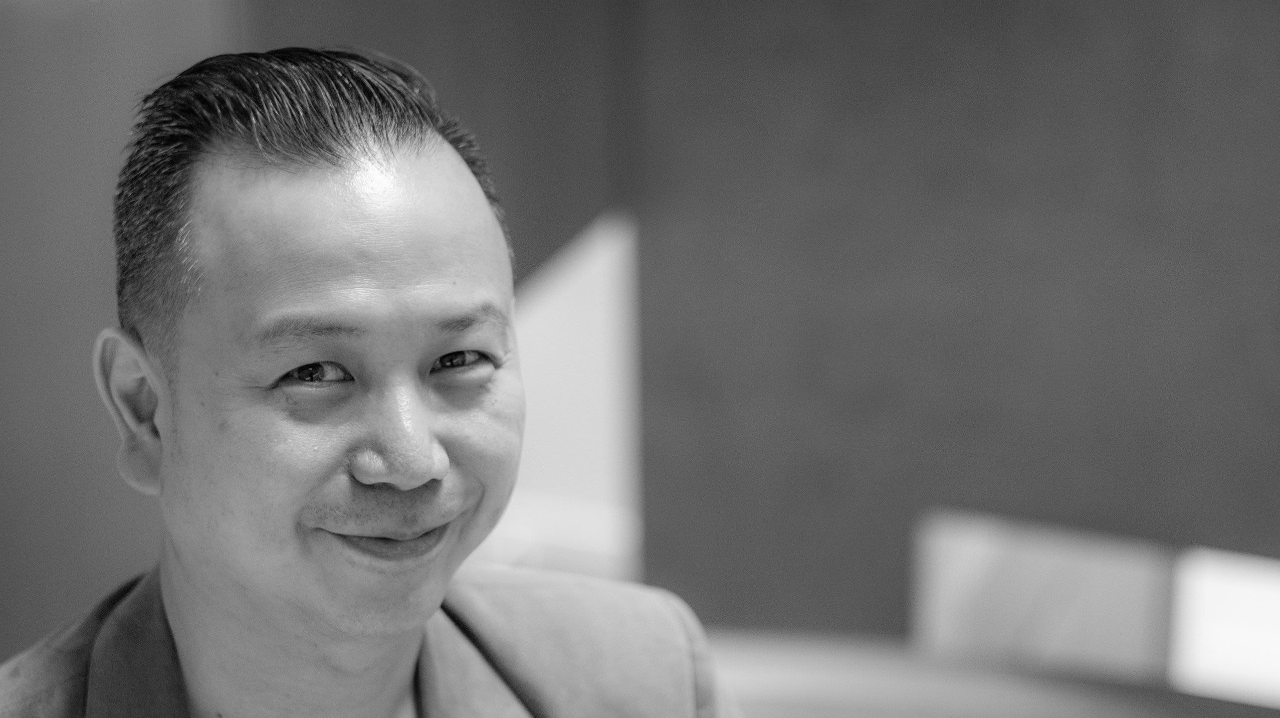 A black and white image of Gerald smiling, standing on the steps that lead down to the engineering labs.