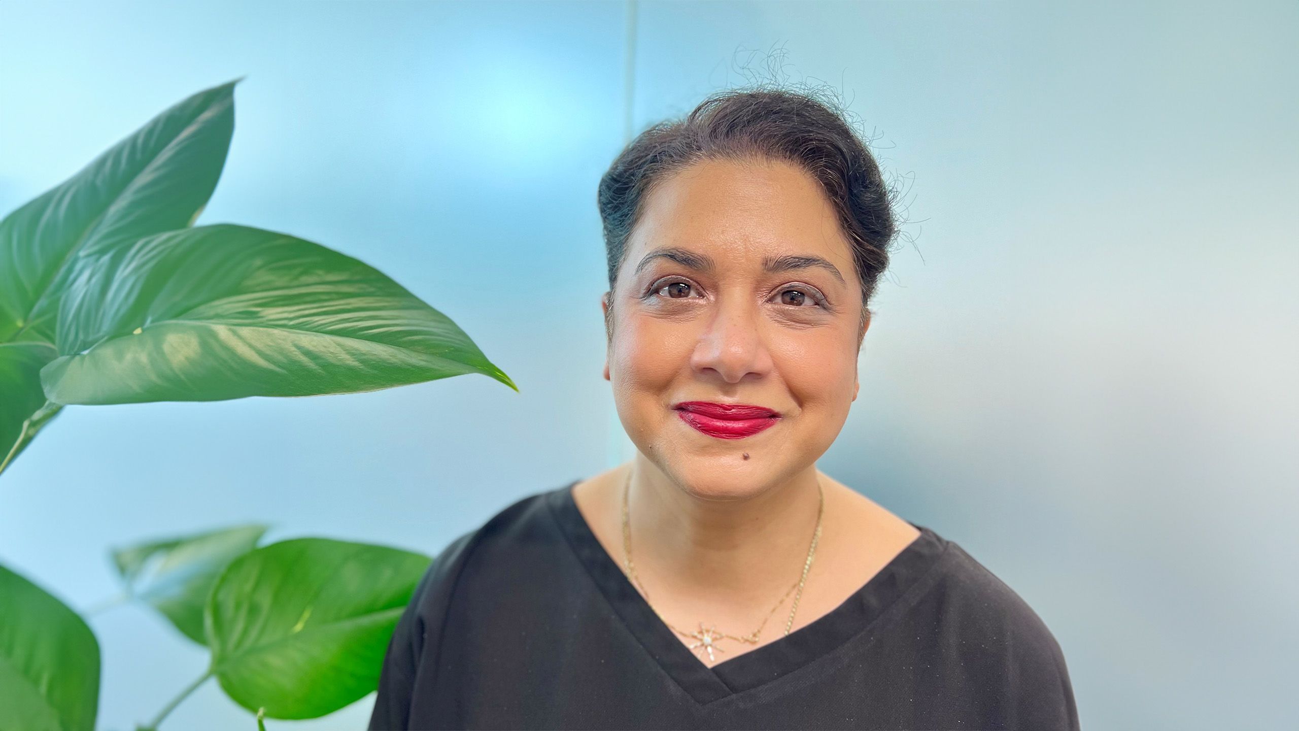Dr Monica Malik smiles in a black top and silver necklace