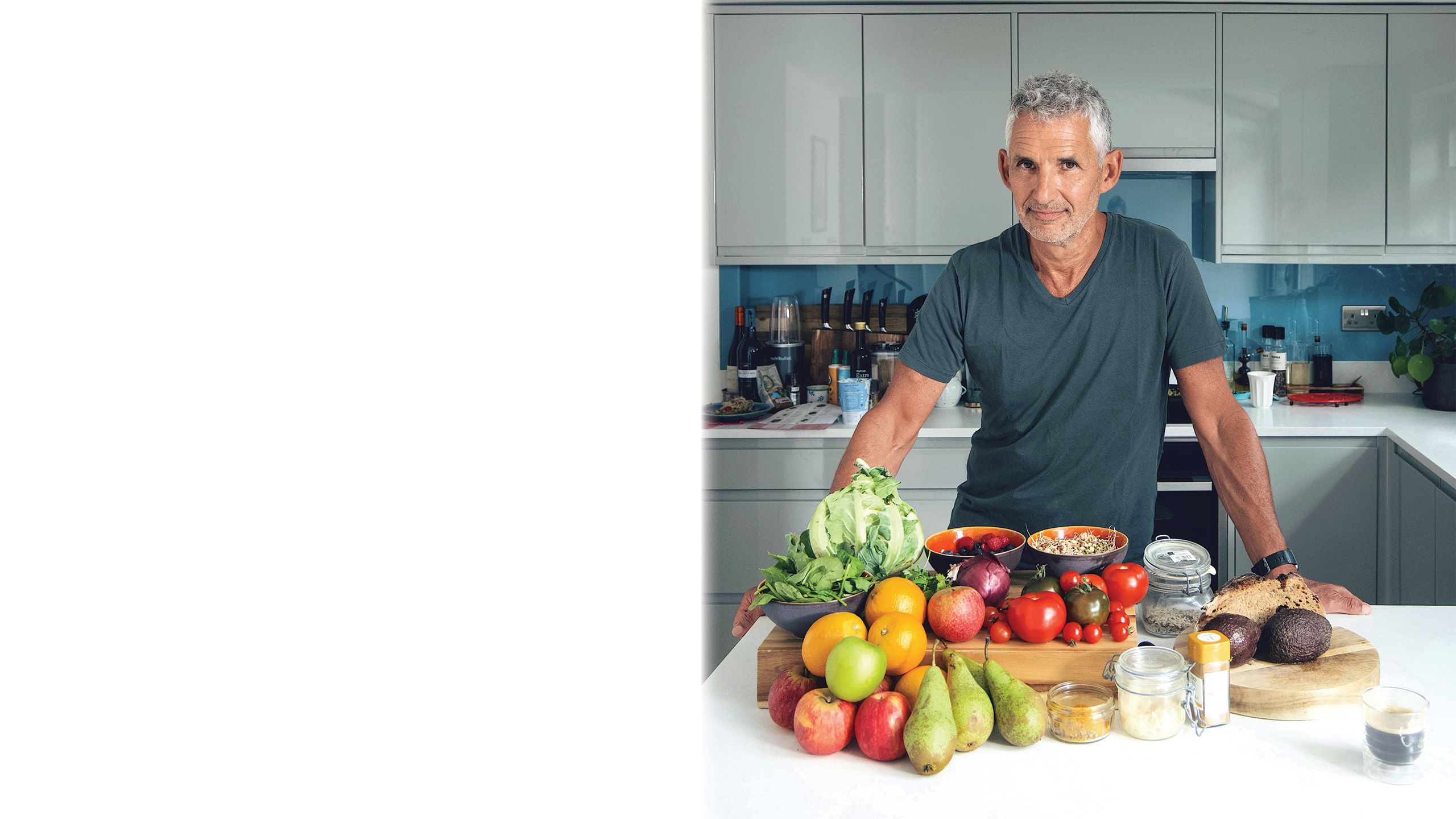 Tim is standing in a kitchen. In front of him is an array of fruit and vegetables.