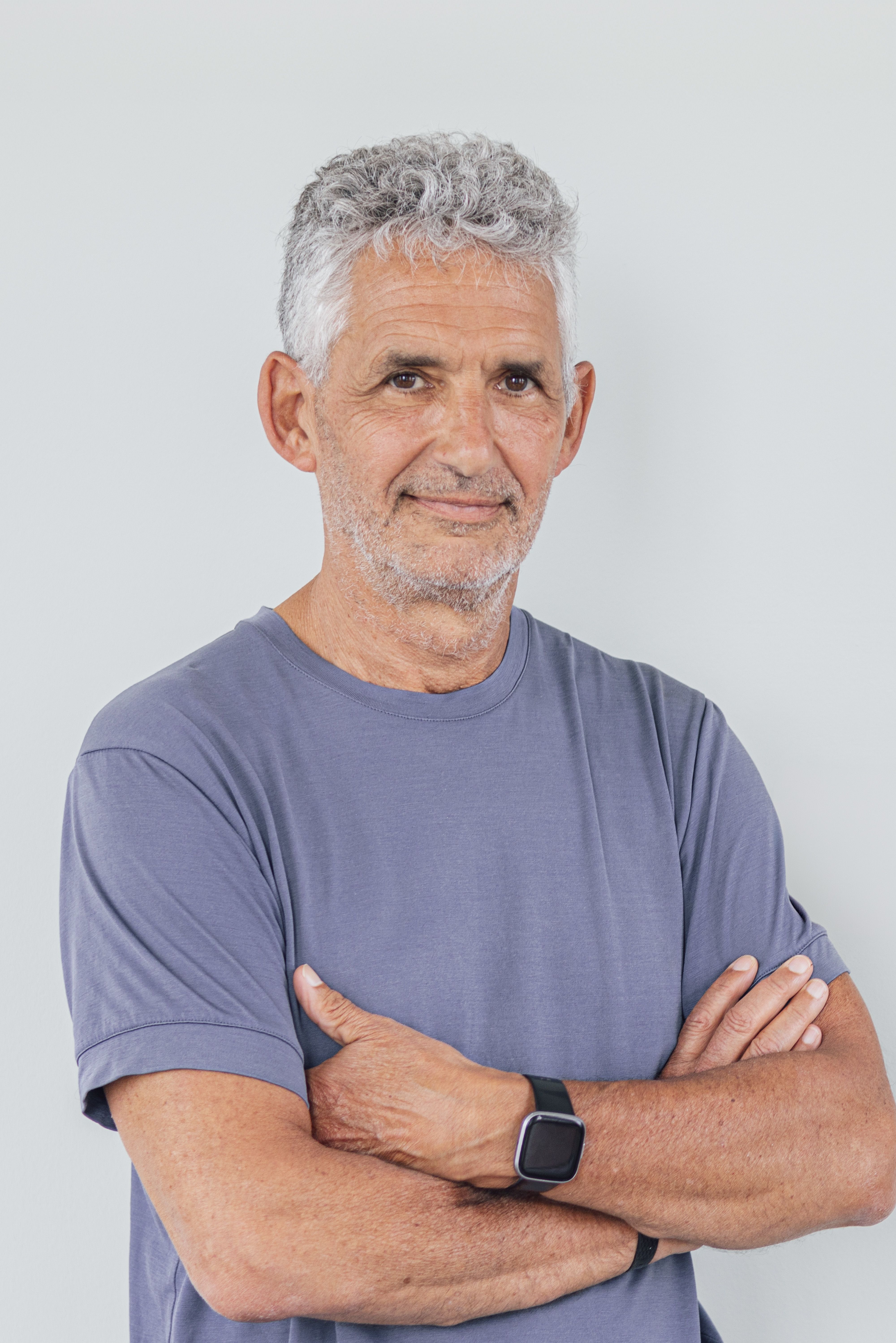 Tim once again stands with his arms folded, but this time he is smiling.