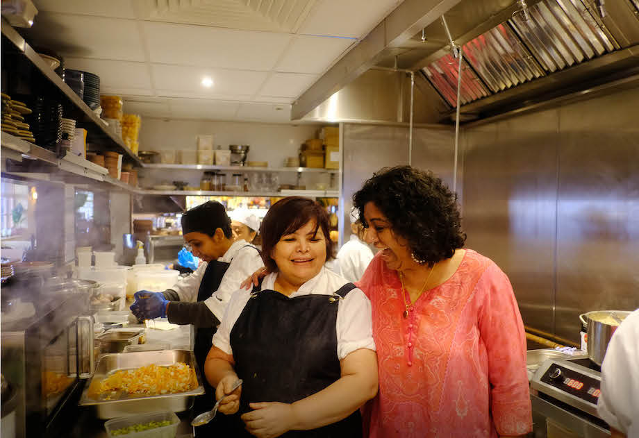 Asma and one of her chefs, smiling and busy in the kitchen