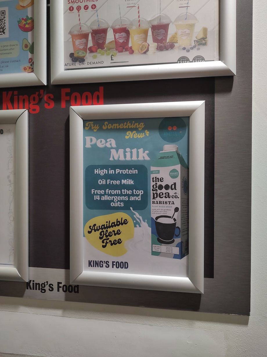 Noticeboard on King's College London's Strand Campus with a framed poster of The Good Pea Co milk product
