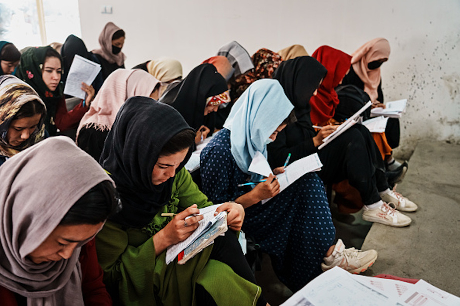 Afghan women in traditional dress studying in a classroom, making notes