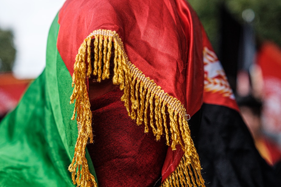 A woman wearing a brightly coloured green and red Hijab, face covered